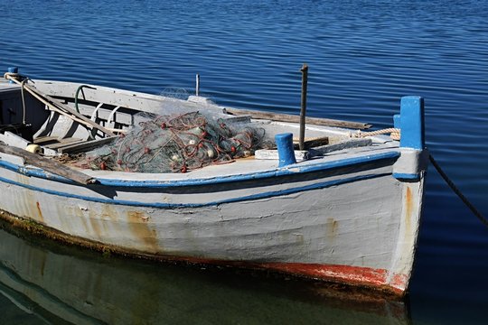 Older wooden white fishing boat with fishnet and oar 