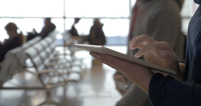 Walking With Tablet Computer In Airport Lounge