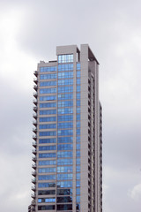 Fototapeta premium Residential building with blue windows on cloudy sky background