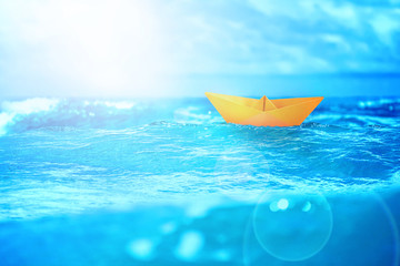 close up sea water surface with yellow paper boat