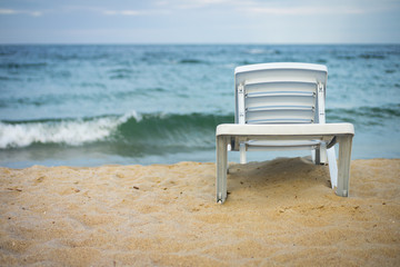 Plastic white lounge chair on empty beach