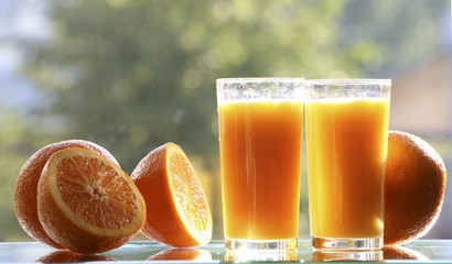 Oranges and orange juice on a green background.