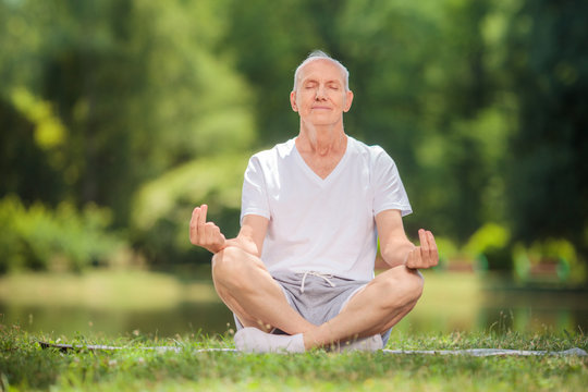 Calm Senior Man Meditating In A Park