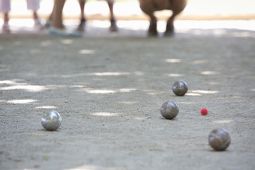 A boules game in progress on the sandy ground in the shade.