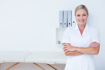Happy doctor looking at camera with arms crossed 