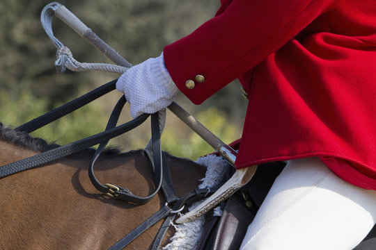 A Master of Foxhounds in a traditional hunting coat, on horseback. 