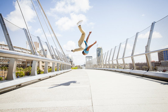 Young man somersaulting on a bridge.
