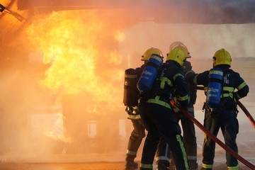 Naklejka premium firefighters fighting large factory fire