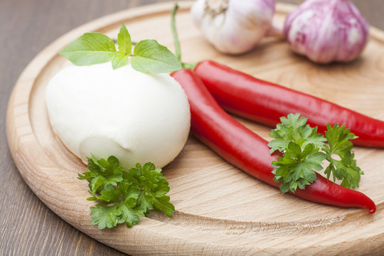 Mozzarella with herbs, noodles, fresh vegetables, chilli, garlic on a wooden round board, selective focus