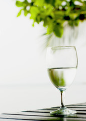 Glass of pure water on a dark table on the beach with a palm tre