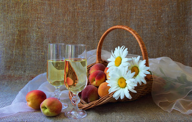 Two glasses of white wine, peaches and bunch of daisies..