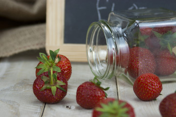 Stawberries in a jar and spilt on table