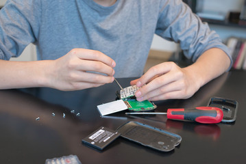 Close up of hands repairing  or disassembling a mobile phone