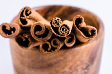 close up of cinnamon on wooden bowl isolated on white