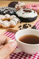 Hand Holding Cup of Coffee During Doughnut or Donut Coffee Break