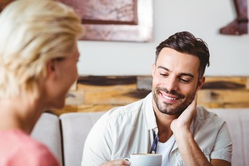 Couple with coffee cup sitting on sofa