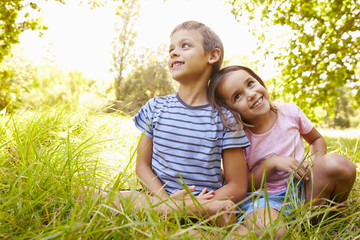 Fototapeta premium Siblings sitting outdoors on a sunny day