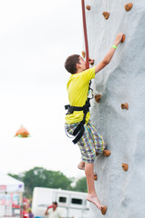 Obraz na płótnie Canvas child wearing a harness climbing a rock climbing wall