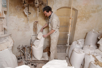 miller puts flour in a bag to weigh it on a balance in the mill