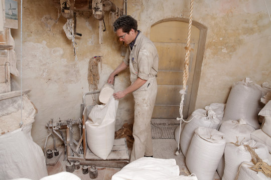 Miller Puts Flour In A Bag To Weigh It On A Balance In The Mill