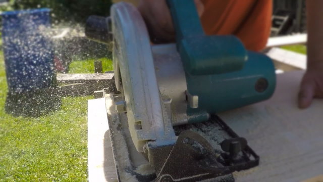 Handyman using hand-held saw machine outdoors.