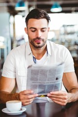  Young man having cup of coffee reading newspaper