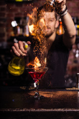 The bartender makes a cocktail of fire. - obrazy, fototapety, plakaty