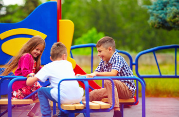 Fototapeta na wymiar happy friends, kids having fun on roundabout at playground