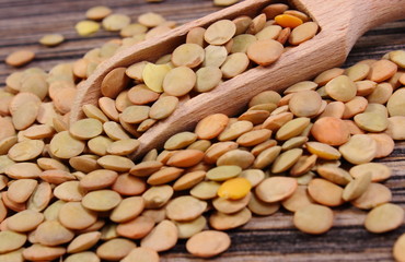 Heap of green lentil with spoon on wooden background