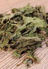 Heap of dried nettle on wooden surface
