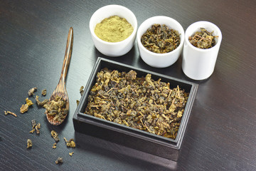 Dry tea in box wooden, dry tea on wooden spoon and green tea powder.