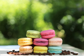 Colorful french macarons with coffee on the nature background