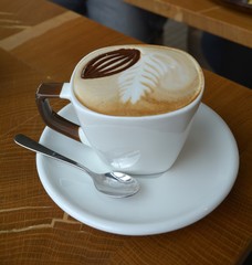Delicious cappuccino in white cup on the wooden table