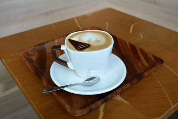 Delicious cappuccino in white cup on the wooden table