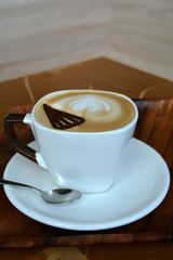 Delicious cappuccino on a white cup on a wooden table