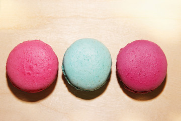 Traditional french pink and blue macarons with sun shadows on wooden background