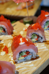 Sushi roll with tuna and tobiko on a wood plate.