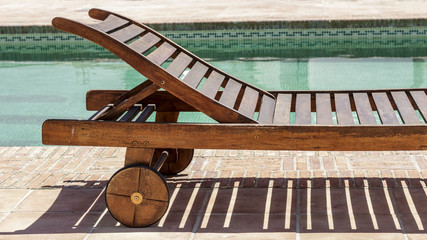 Sun recliner beside a swimming pool. Summertime.