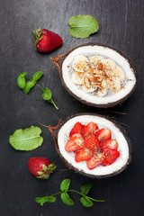 Chia seeds coconut pudding with berries and fruit on black stone background.  top view