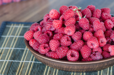 fresh ripe raspberries in clay plate