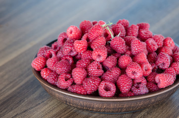 fresh ripe raspberries in clay plate