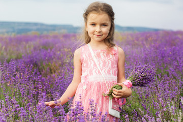 Cute little child girl in lavender field with purple bouquet
