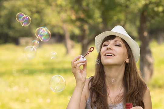 Young pretty caucasian woman having fun with blowing bubbles