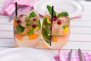 limonade with berries in glassware on wooden table on light blur
