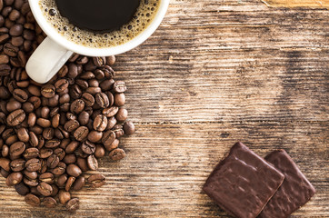 Coffee cup and chocolates on a wooden table