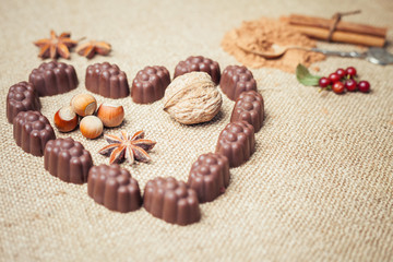 Chocolate candies with liquor in form of heart on background