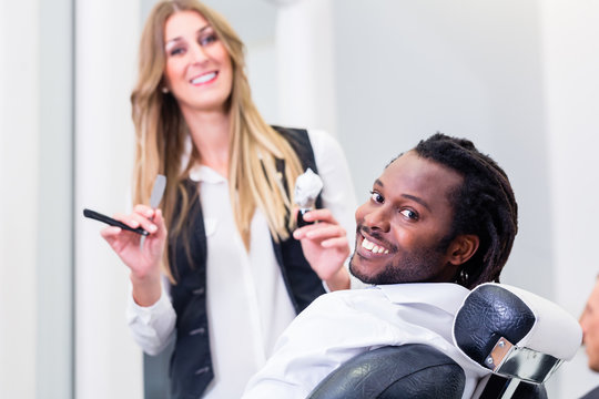 Happy barber and smiling customer in salon
