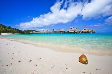 White sand beach and overwater villas in blue tropical lagoon, Bora Bora, French Polynesia, South Pacific 