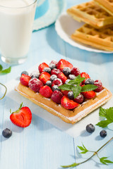 Waffles with strawberry and berry fruit on blue table top view