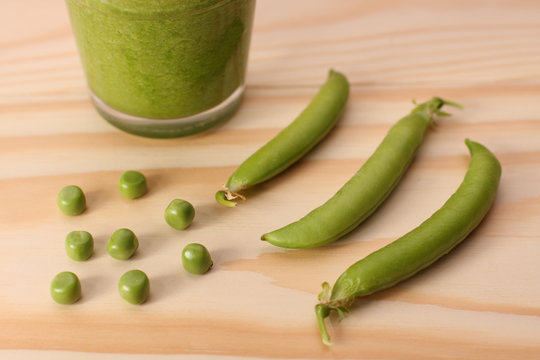 Green peas and and pea pods and green smoothie on wooden table